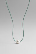 Jungle green colored silk thread necklace with single floating white pearl on grey background by xomango 