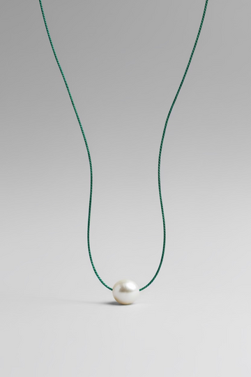 Jungle green colored silk thread necklace with single floating white pearl on grey background by xomango 