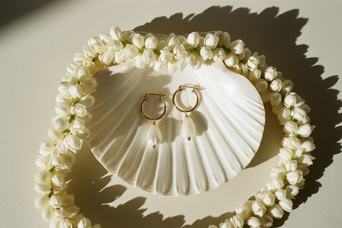 Gold hoop earrings with pearl drops on a warm cream background