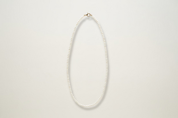 solid Gold pearl necklace on a light gray background