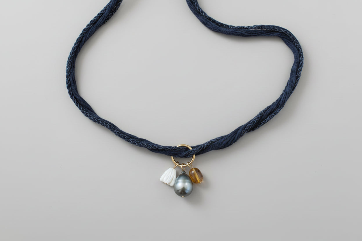Tahitian pearl, mother of pearl Pikake flower, and amber bead hang from a denim blue silk ribbon necklace by xomango
