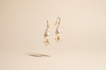 Pearl earrings on a textured stone surface