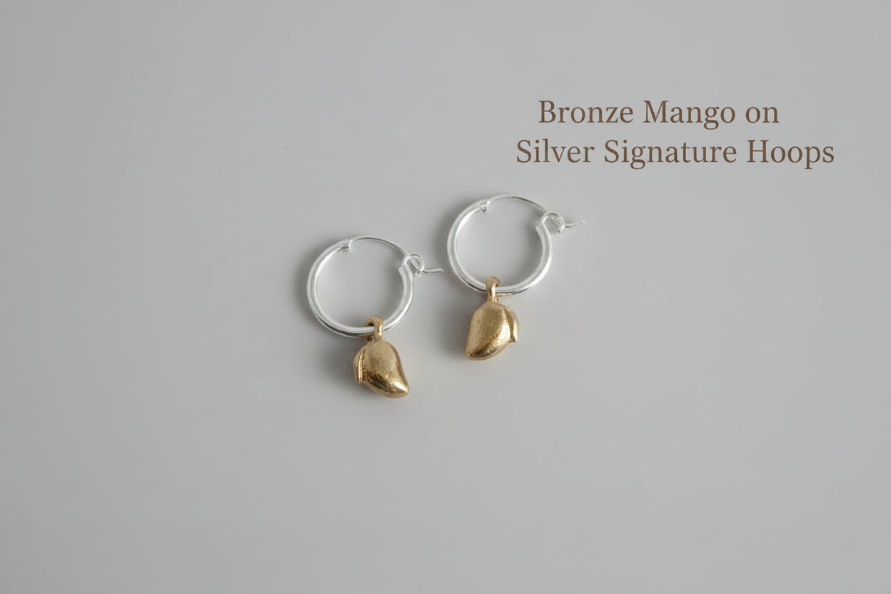 Silver hoop earrings with mango-shaped charms white background by xomango