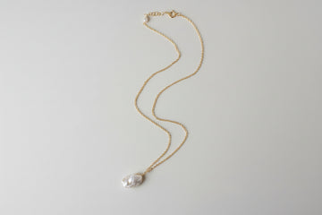 Gold necklace with a pendant on a light gray background