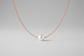 light brown colored silk thread necklace with single floating white pearl on grey background by xomango 