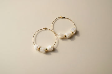 Pair of hoop earrings with floral designs on a cream background